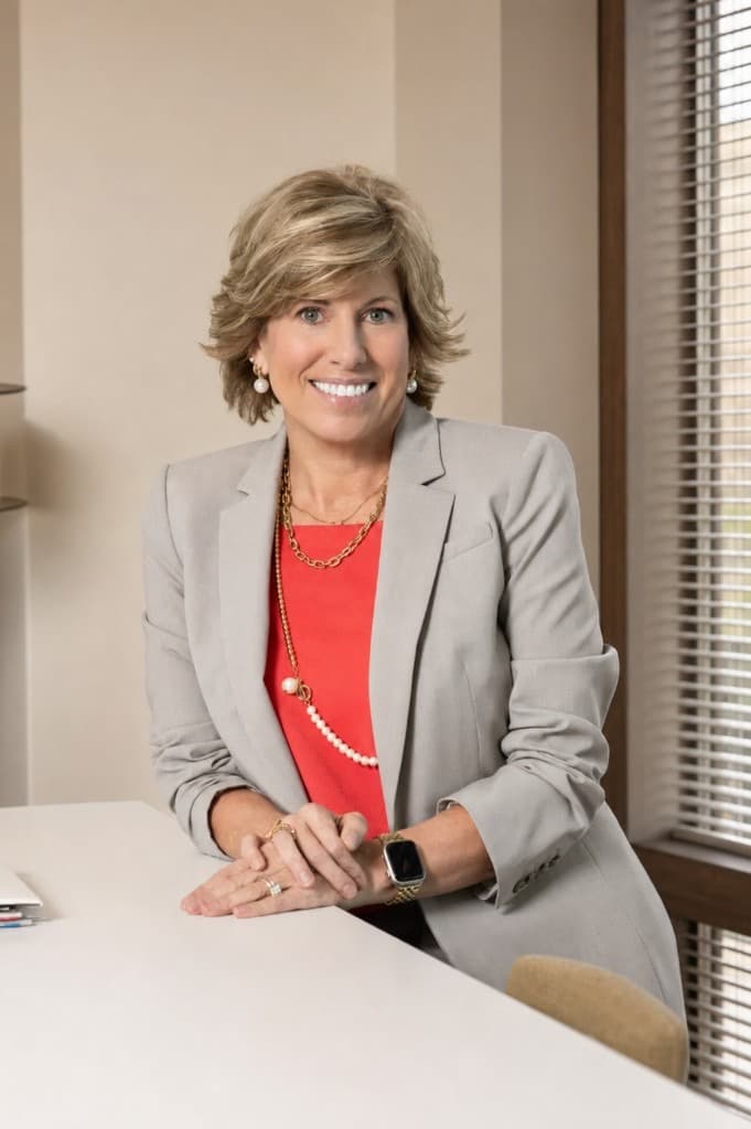 Kelly, college consultant at CollegePrep, seated at a desk in a coral blouse and grey blazer